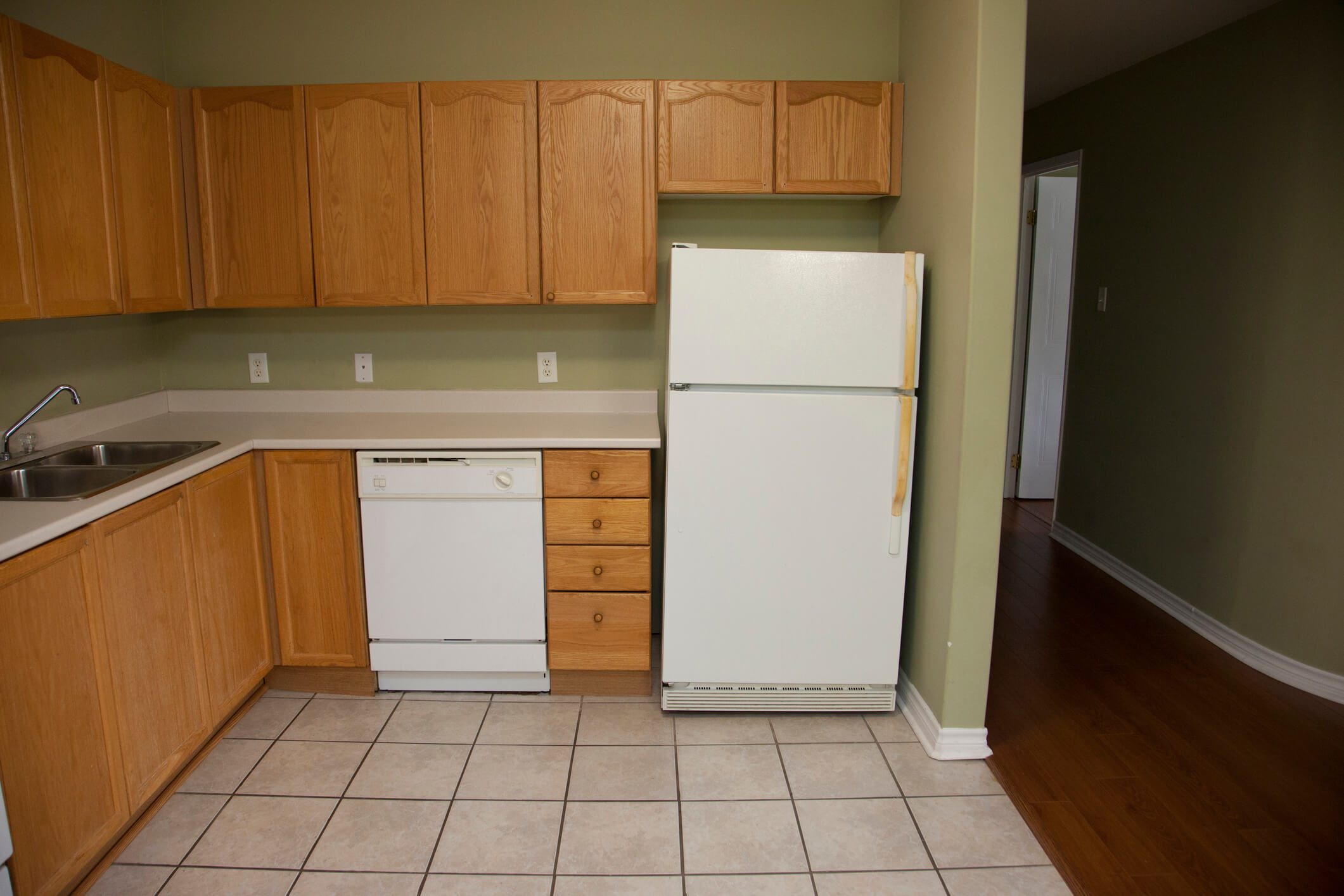 Empty kitchen with fridge and dishwasher.