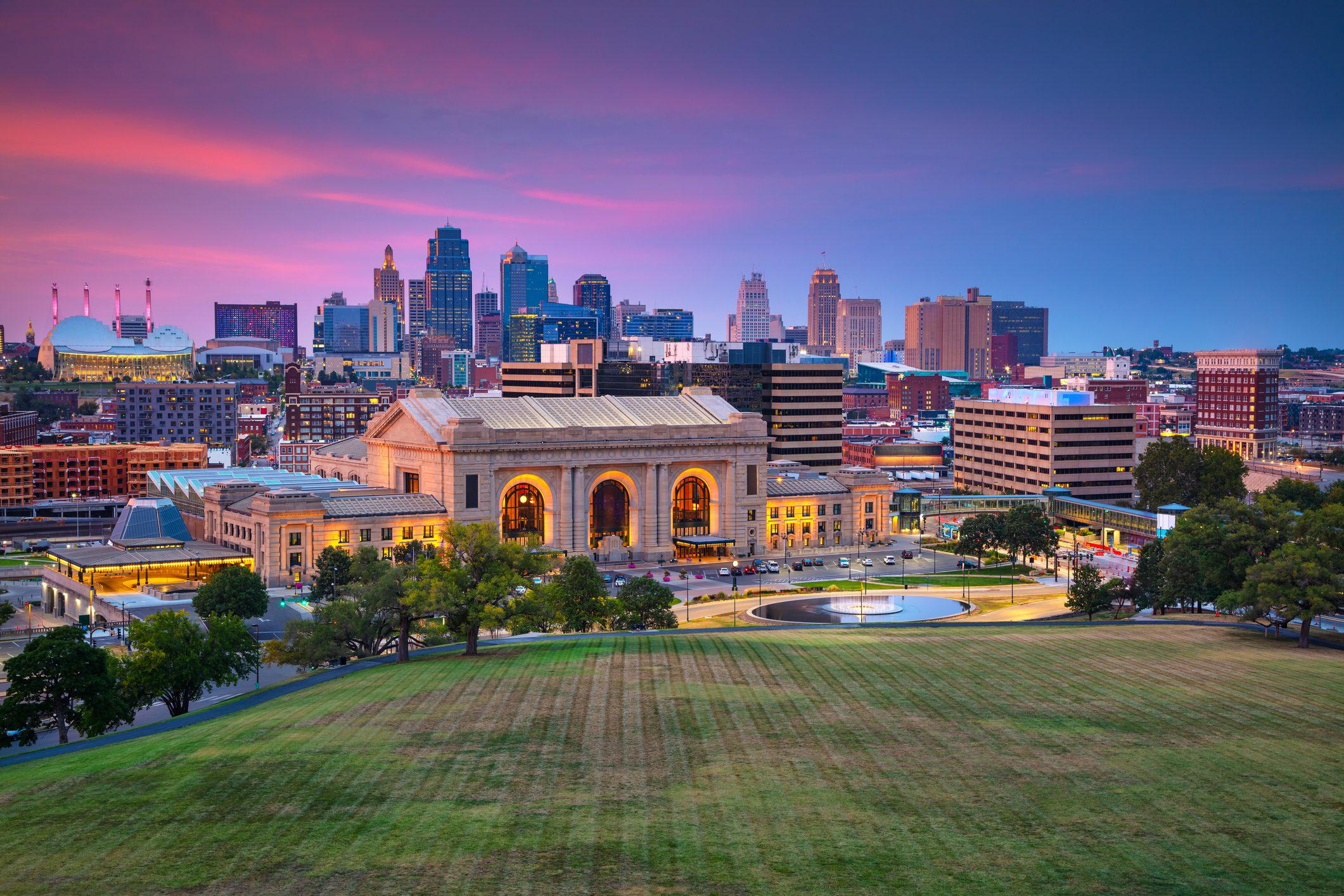 City skyline at sunset with a historic building in the foreground.