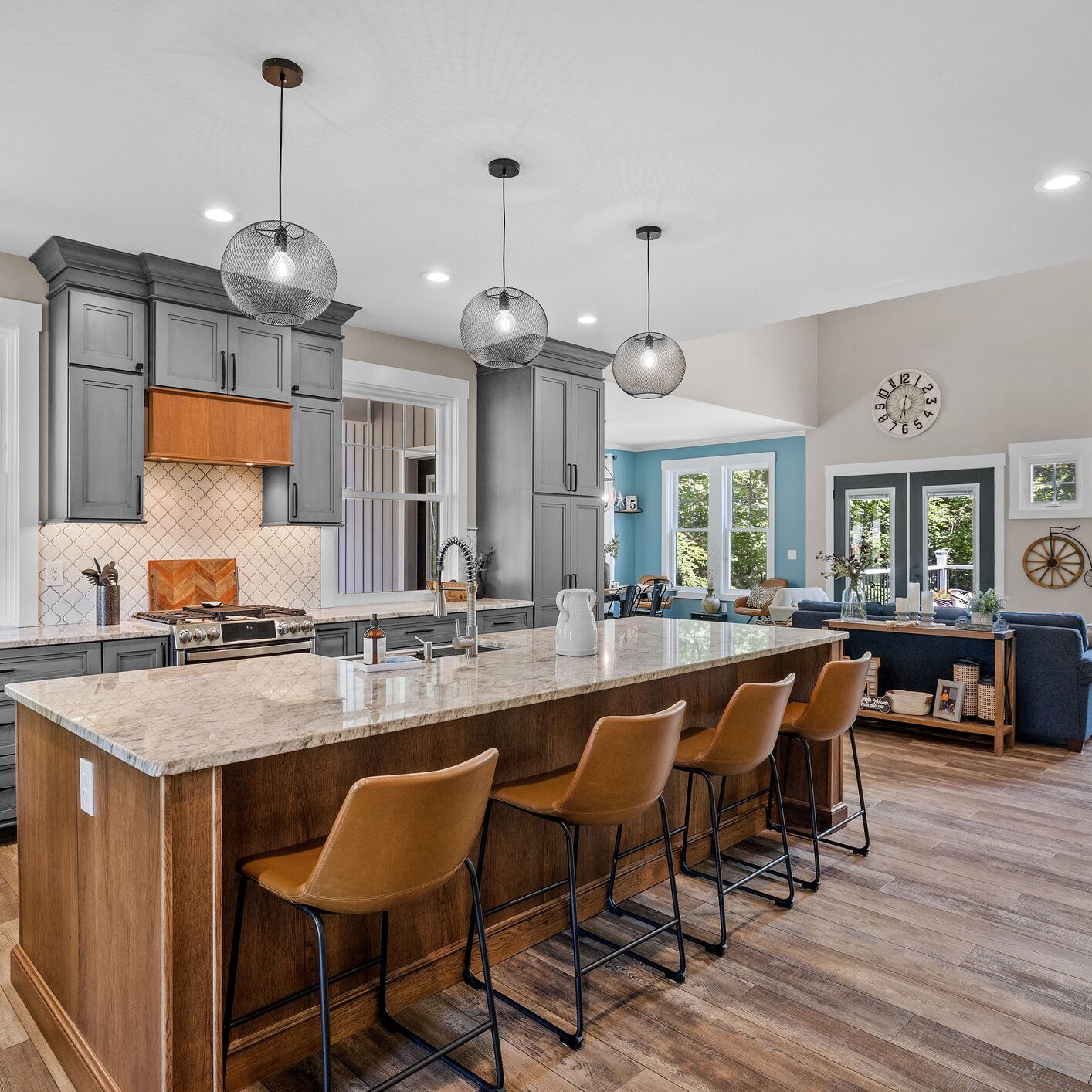 Modern kitchen island with leather stools and pendant lighting.