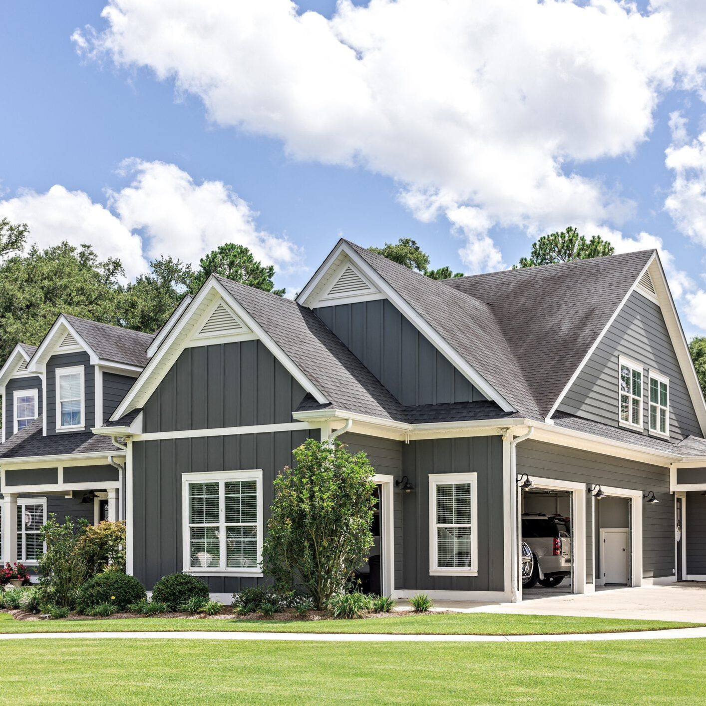 Modern gray house with a spacious garage and well-kept lawn.