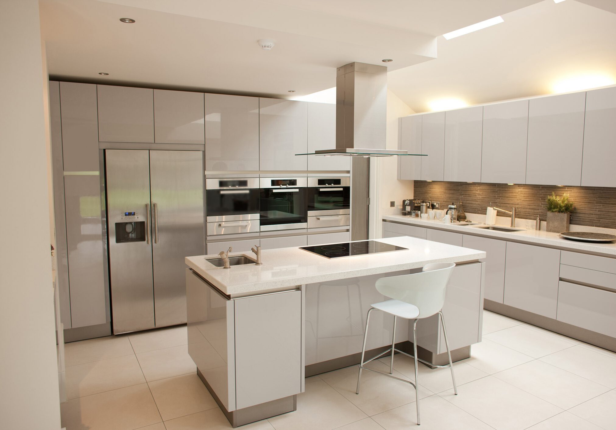 Modern white kitchen with island and integrated appliances.