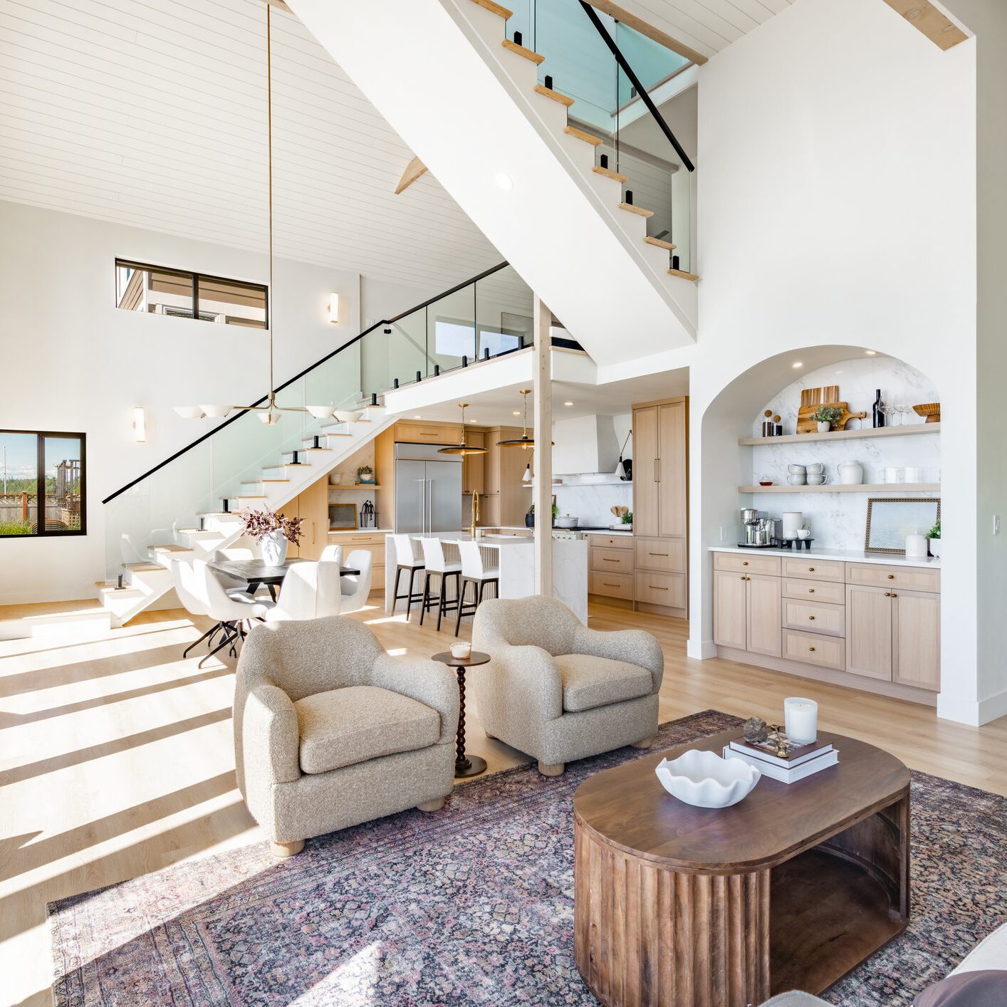 Bright modern living room with glass staircase and cozy seating.