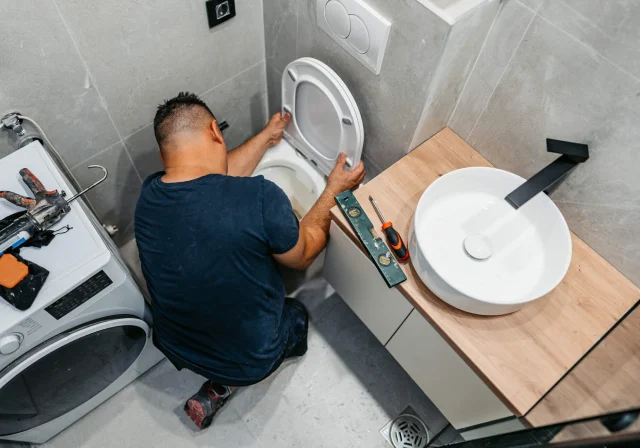 Man fixing toilet in modern bathroom